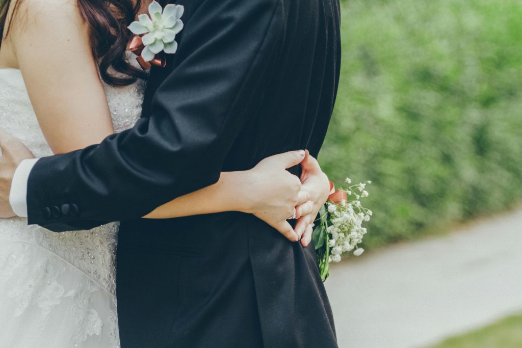 Close-up of a bride and groom hugging in a lush Kowloon garden, capturing wedding romance.